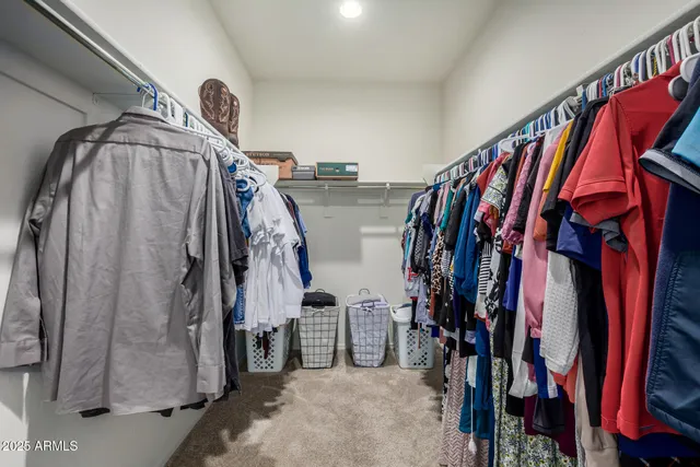 a view of walk in closet with clothes and shoes