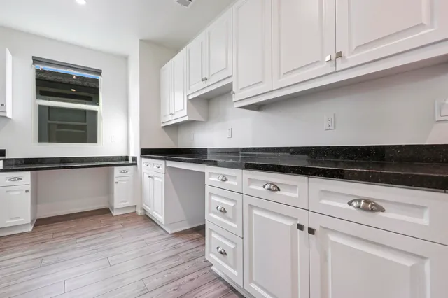 a kitchen with granite countertop white cabinets and a stove with wooden floor