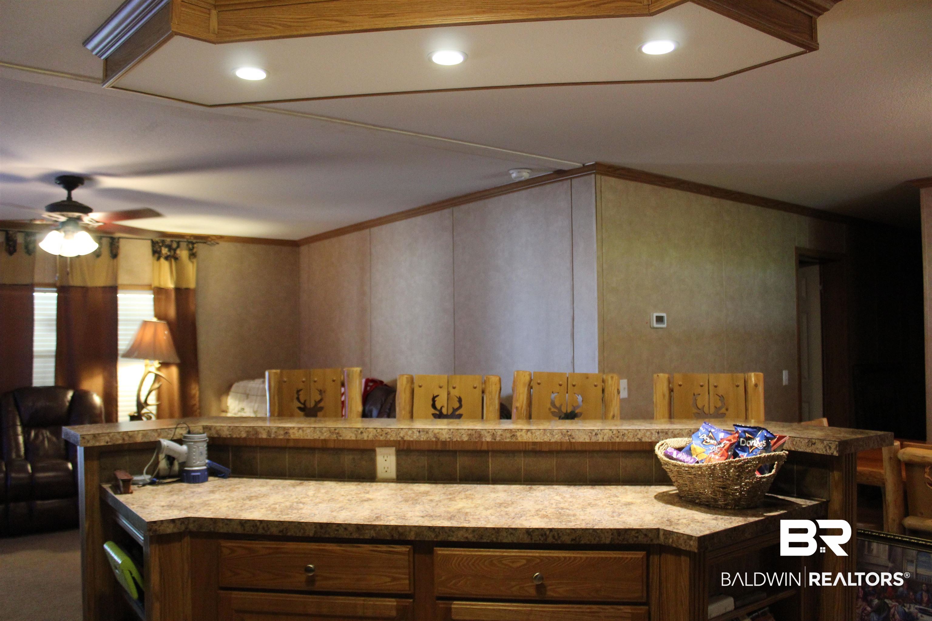 7258 Henderson Road Lowndesboro, AL 36752 - Photo 12 of 22 Kitchen with ornamental molding, light countertops, a ceiling fan, and brown cabinets