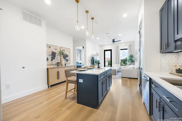 a large kitchen with a large counter top a sink stainless steel appliances and cabinets