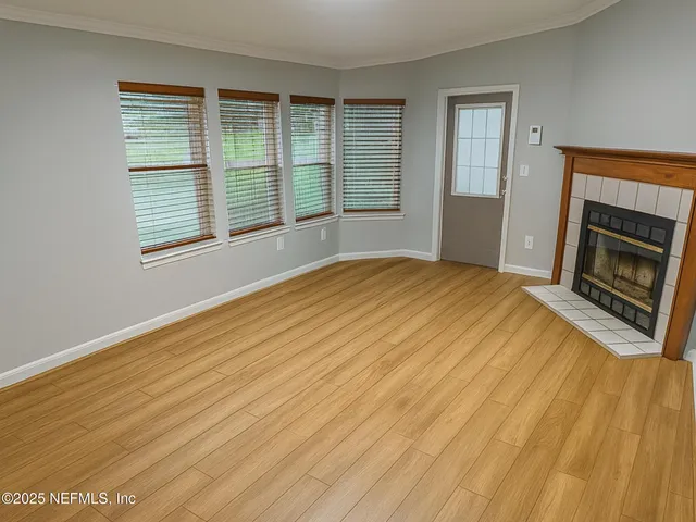 a view of an empty room with wooden floor and a window