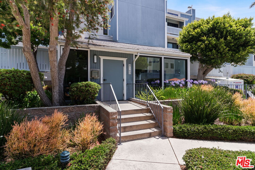 a front view of a house with plants and garden