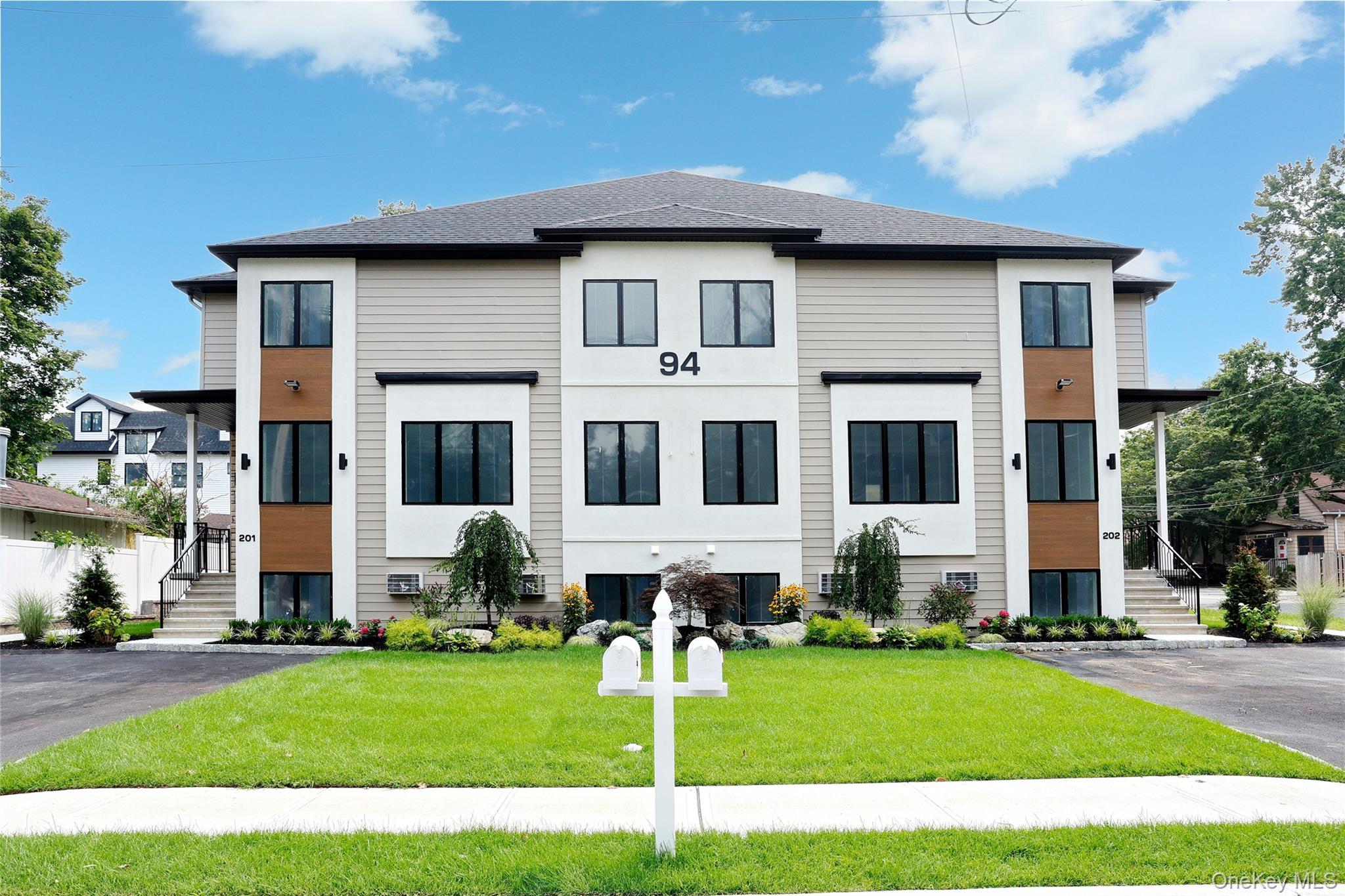 94 Fairview Avenue, Unit 201 Spring Valley, NY 10977 - Photo 1 of 1 a white house with a big yard and potted plants