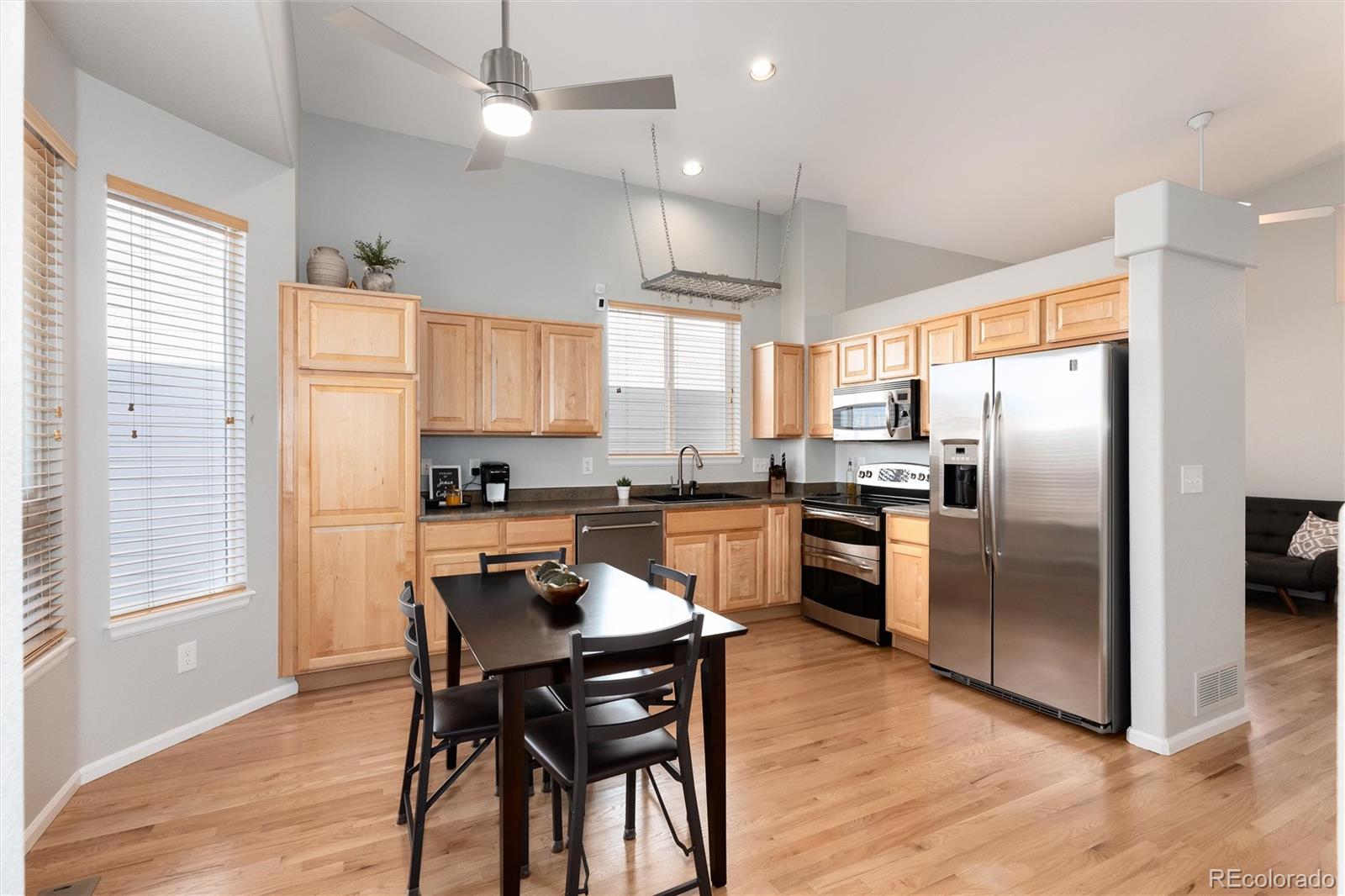 10627 Cherrybrook Circle Highlands Ranch, CO 80126 - Photo 18 of 44 a kitchen with granite countertop a refrigerator a stove a sink dishwasher a dining table and chairs with wooden floor