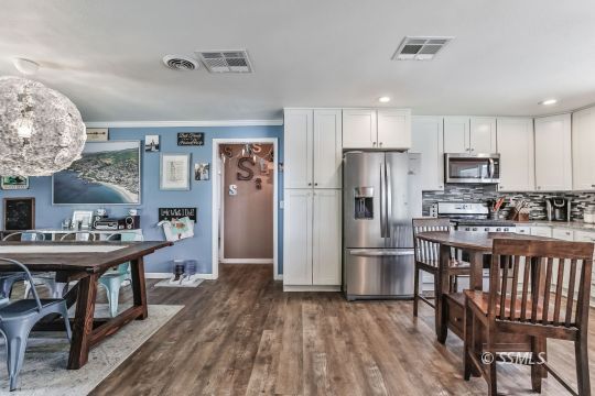700 Sherri Street Ridgecrest, CA 93555 - Photo 11 of 34 a kitchen with stainless steel appliances a dining table chairs stove refrigerator and cabinets