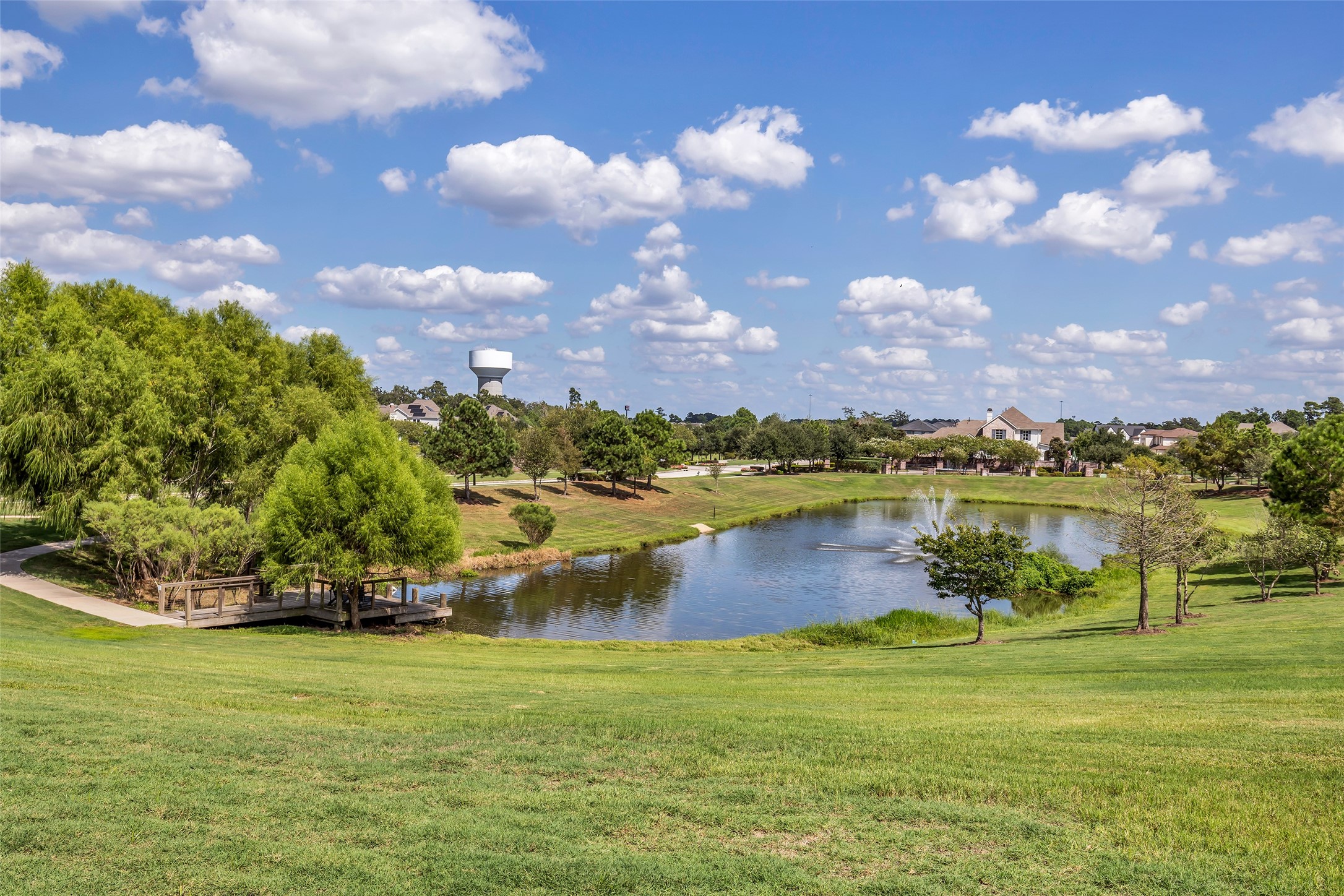 2344 Hagerman Road Conroe, TX 77384 - Photo 26 of 27 Serene parkland setting with a picturesque pond, fountain, and lush greenery, perfect for relaxation and outdoor enjoyment.