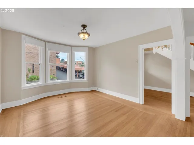 a view of an empty room with window and wooden floor
