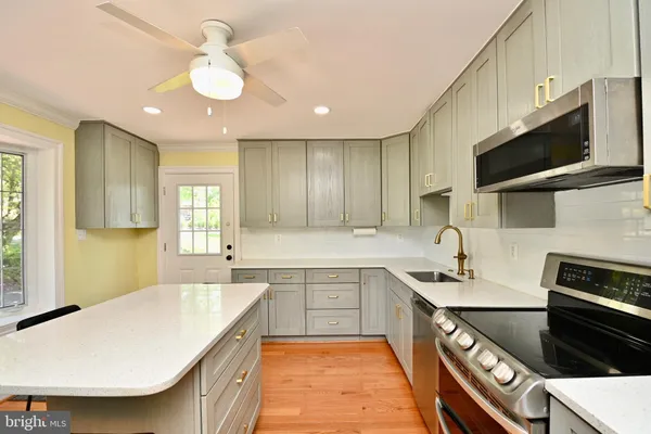 a kitchen with kitchen island granite countertop a sink stainless steel appliances and cabinets