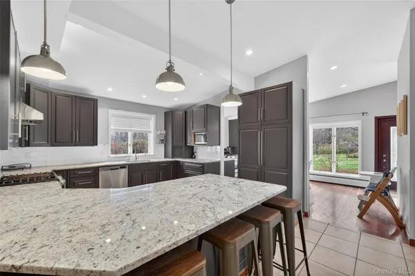 a kitchen with stainless steel appliances kitchen island granite countertop a table chairs and a refrigerator