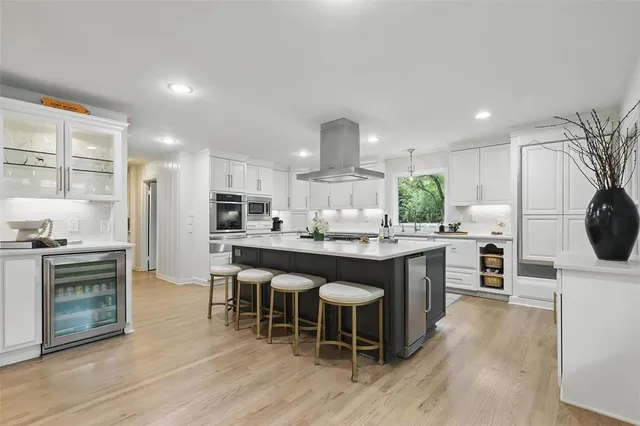 a kitchen with stainless steel appliances granite countertop a stove top oven a refrigerator a sink and a dining table with wooden floor