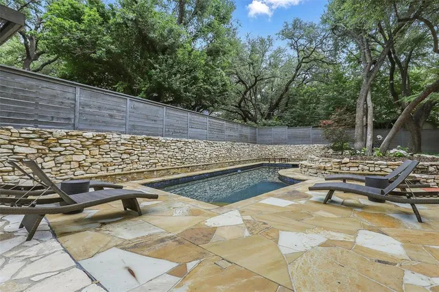 a view of a swimming pool with a patio and trees