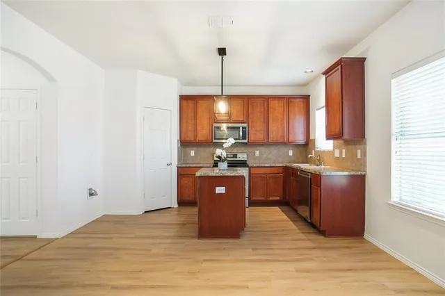 a kitchen with stainless steel appliances granite countertop a refrigerator a sink dishwasher a stove with wooden cabinets and floor