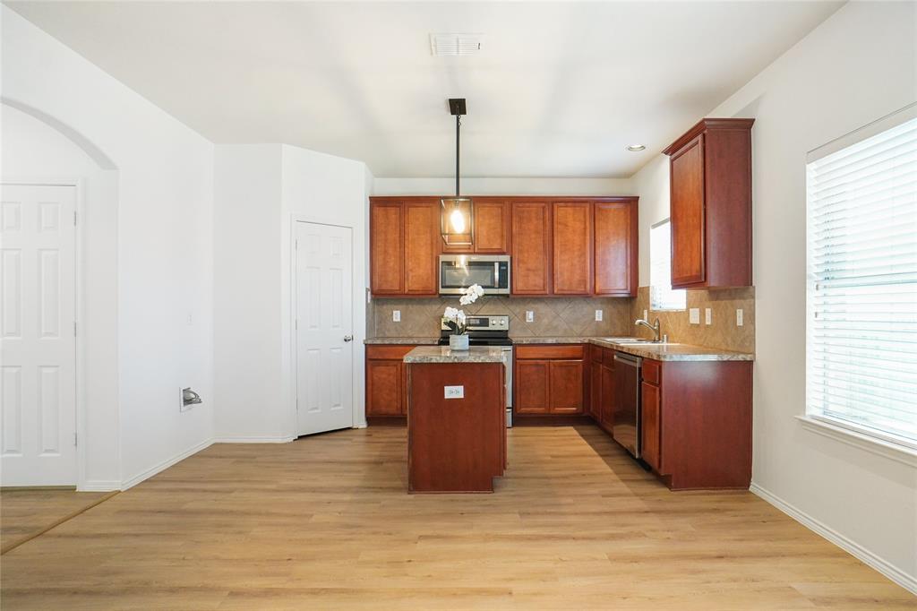 3752 Jade Street Fort Worth, TX 76244 - Photo 12 of 34 a kitchen with stainless steel appliances granite countertop a refrigerator a sink dishwasher a stove with wooden cabinets and floor