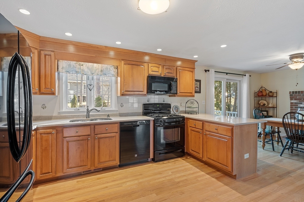 92 Stonegate Road, Unit 92 Chelmsford, MA 01824 - Photo 11 of 32 a kitchen with stainless steel appliances granite countertop a stove top oven a sink dishwasher a refrigerator and a dining table with wooden floor
