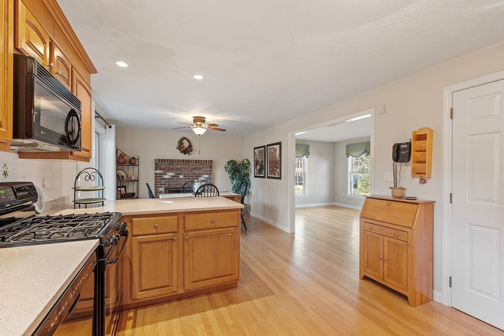 92 Stonegate Road, Unit 92 Chelmsford, MA 01824 - Photo 12 of 32 a kitchen with a refrigerator a stove top oven a sink dishwasher and wooden cabinets with wooden floor