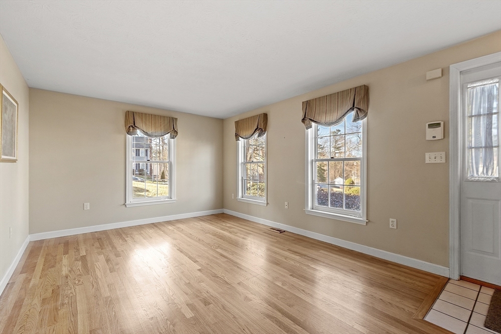 92 Stonegate Road, Unit 92 Chelmsford, MA 01824 - Photo 6 of 32 a view of an empty room with a window and wooden floor