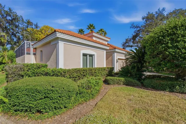 a view of a white house with table and chairs potted plants and palm trees