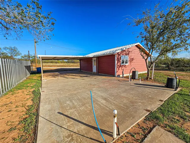 a view of an empty room with window and chandelier fan