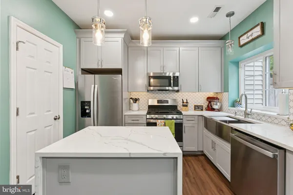 a kitchen with a sink a counter top space stainless steel appliances and cabinets
