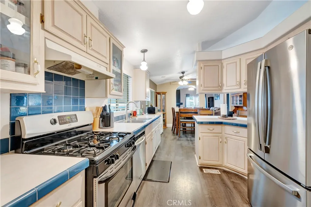 1051 Site, Unit 26 Brea, CA 92821 - Photo 17 of 46 a kitchen with stainless steel appliances a stove a sink dishwasher a refrigerator white cabinets and wooden floor