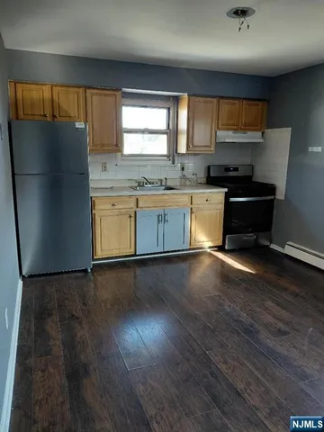 a kitchen with granite countertop wooden floors stainless steel appliances a window and a sink