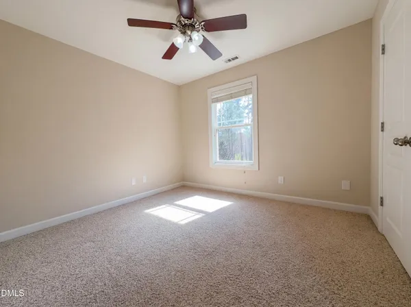 an empty room with windows and fan