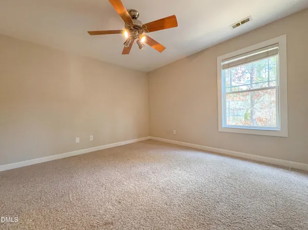 an empty room with a window and a fan