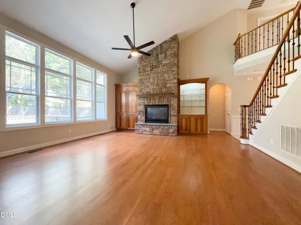 a view of an empty room with wooden floor fireplace and a window