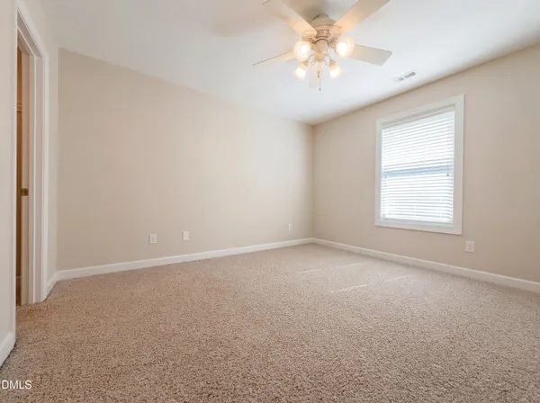 an empty room with a chandelier fan and windows