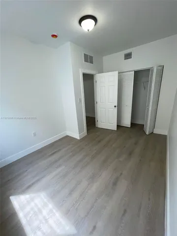 an empty room with wooden floor and closet