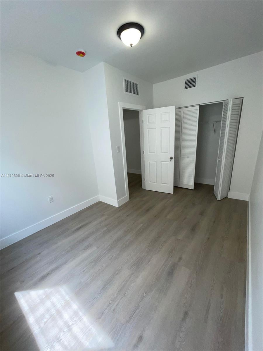 858 Northwest 3rd Street, Unit 112 Miami, FL 33128 - Photo 11 of 15 an empty room with wooden floor and closet