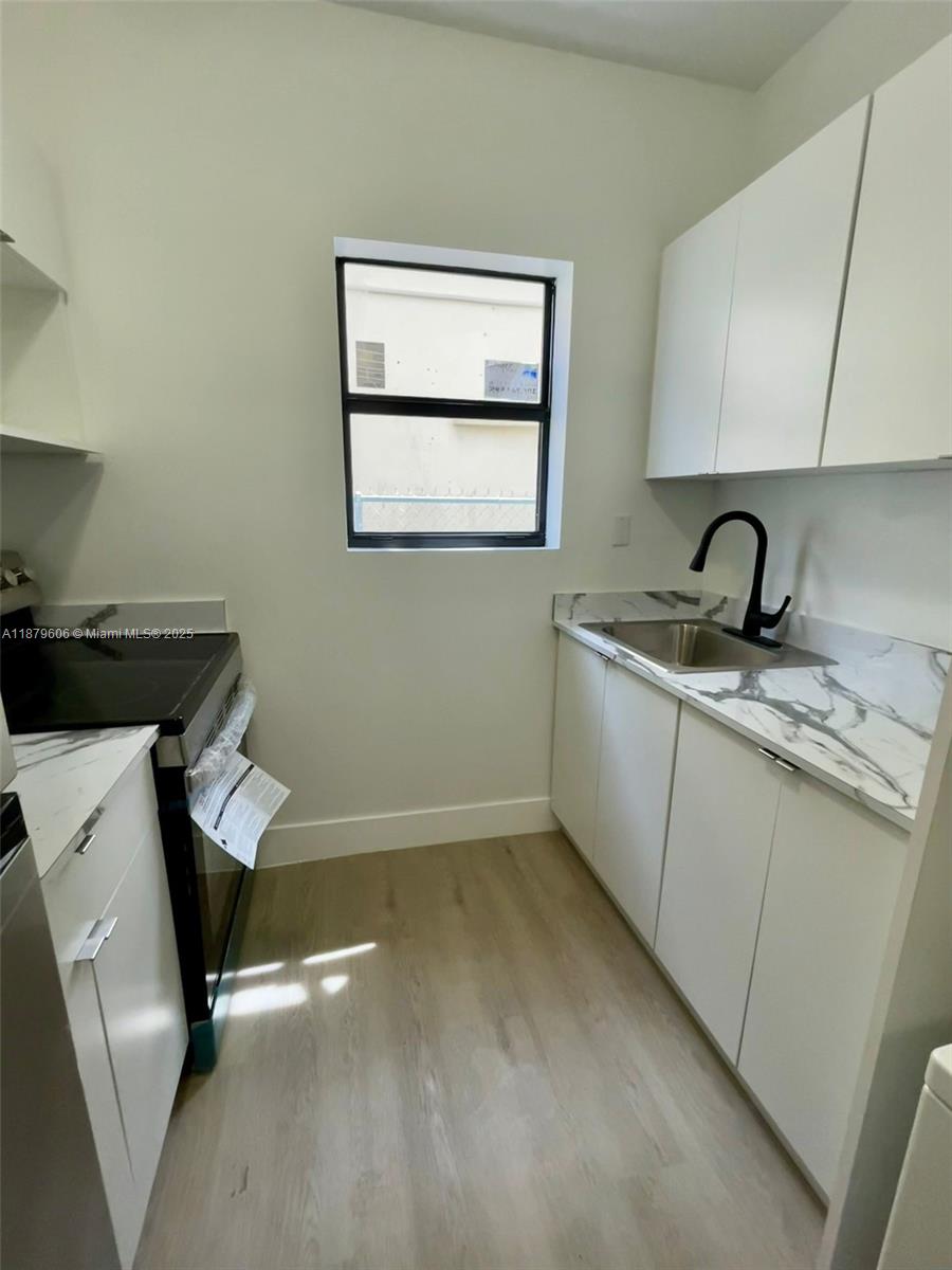 858 Northwest 3rd Street, Unit 112 Miami, FL 33128 - Photo 6 of 15 a room with a sink cabinets and wooden floor