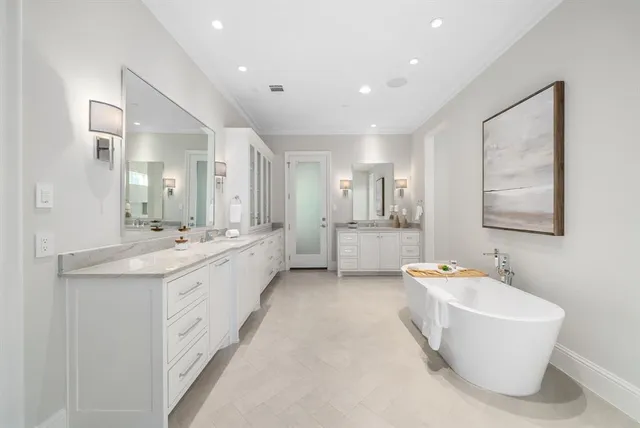 a large bathroom with a tub double vanity sink and mirror
