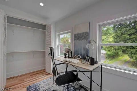 a walk in closet with wooden floor