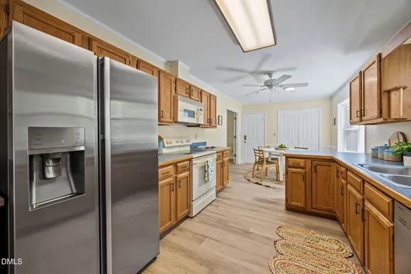 a kitchen with stainless steel appliances granite countertop a refrigerator a sink and white cabinets