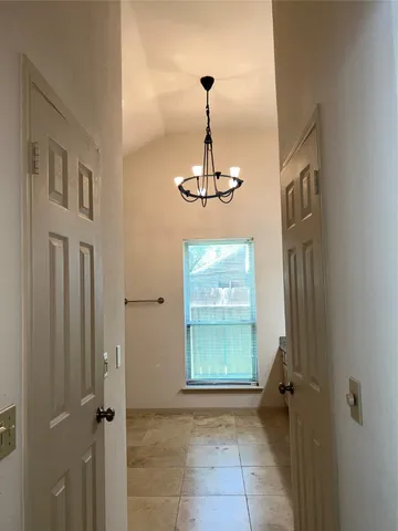 a view of a hallway with windows and chandelier