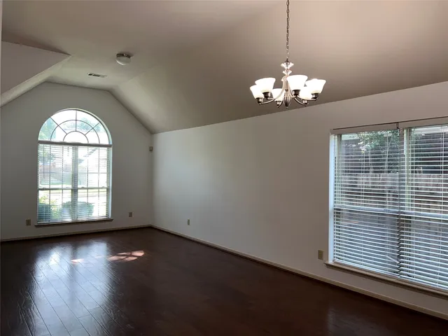 a view of a room with wooden floor chandelier and windows