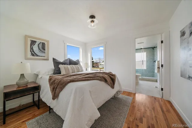 a spacious bedroom with a bed and a lamp on dresser