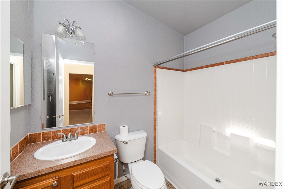 3375 West Rancho Road Golden Valley, AZ 86413 - Photo 28 of 33 a bathroom with a granite countertop sink toilet a mirror and shower