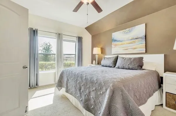 a spacious bedroom with a bed and a lamp