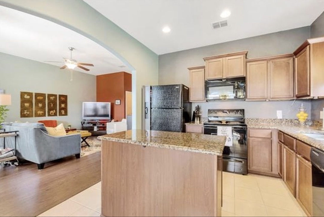 13405 Clara Martin Road Manor, TX 78653 - Photo 26 of 26 Kitchen with black appliances, a kitchen island, light wood finish cabinets, open floor plan, and ceiling fan
