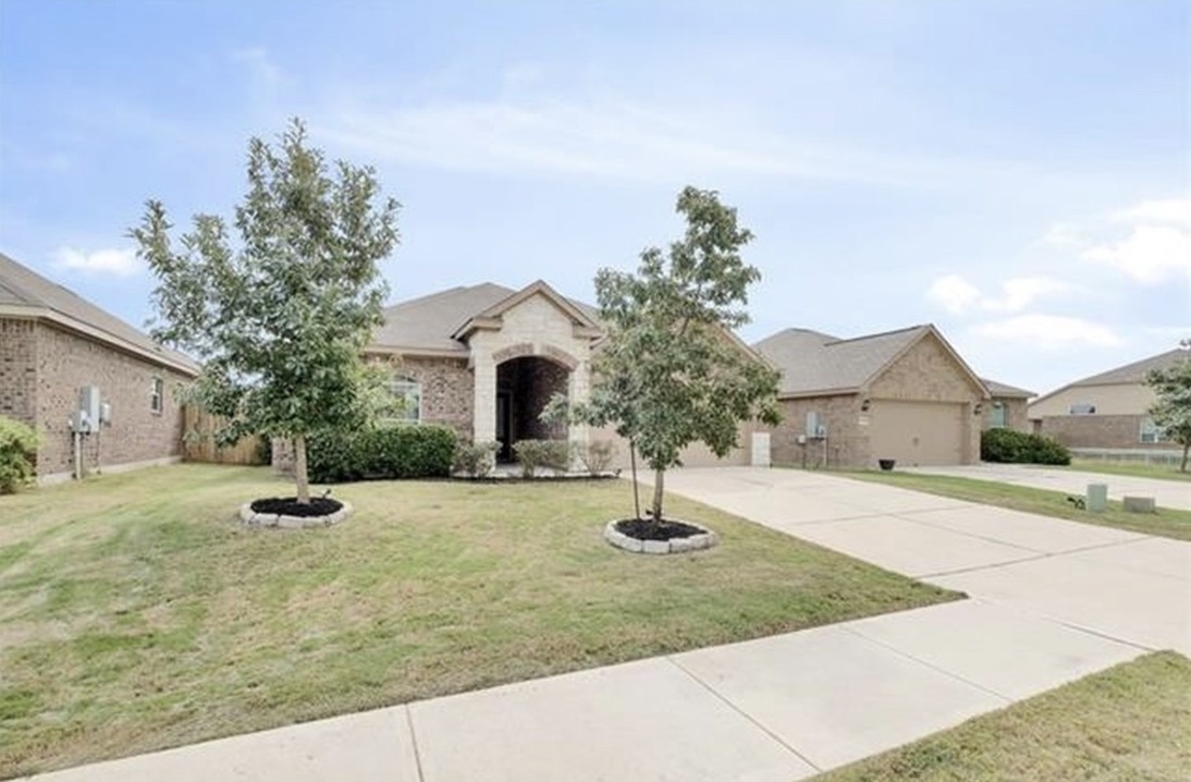 13405 Clara Martin Road Manor, TX 78653 - Photo 2 of 26 View of front of property with a front yard, stone siding, driveway, and a garage