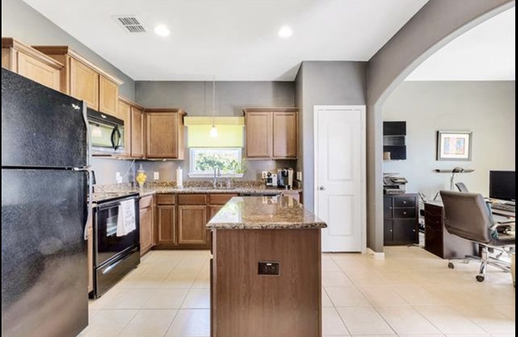 13405 Clara Martin Road Manor, TX 78653 - Photo 5 of 26 Kitchen with black appliances, a desk, a center island, wood finish cabinets, and light stone countertops