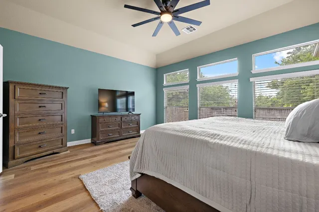 a bedroom with a bed a large window and a flat tv screen