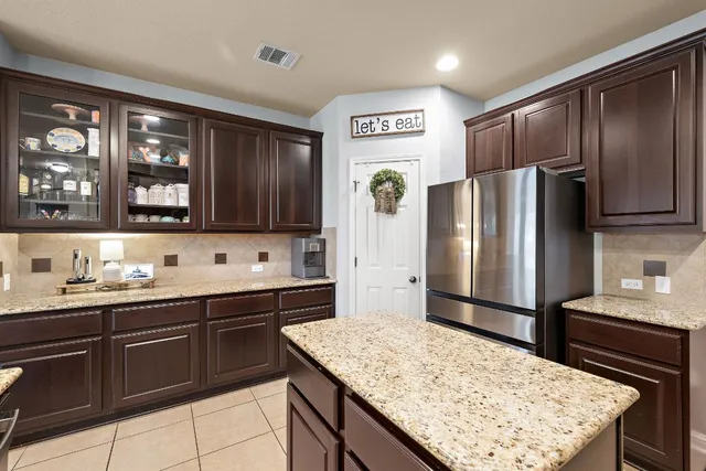 a kitchen with stainless steel appliances kitchen island granite countertop a refrigerator and a sink