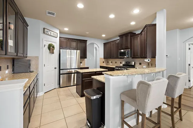 a kitchen with stainless steel appliances granite countertop a refrigerator and a stove top oven