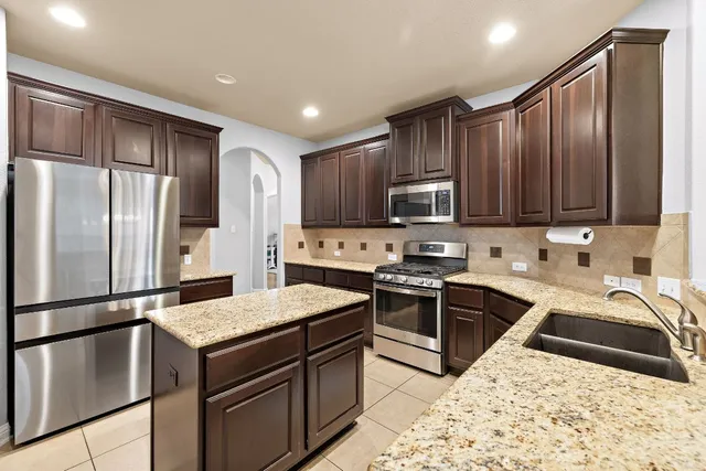 a kitchen with stainless steel appliances granite countertop a refrigerator stove microwave and sink