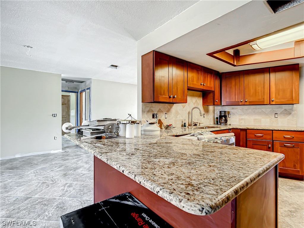 207 Redfish Road Fort Myers Beach, FL 33931 - Photo 11 of 50 a kitchen with kitchen island granite countertop wooden cabinets granite counter tops and a view of living room