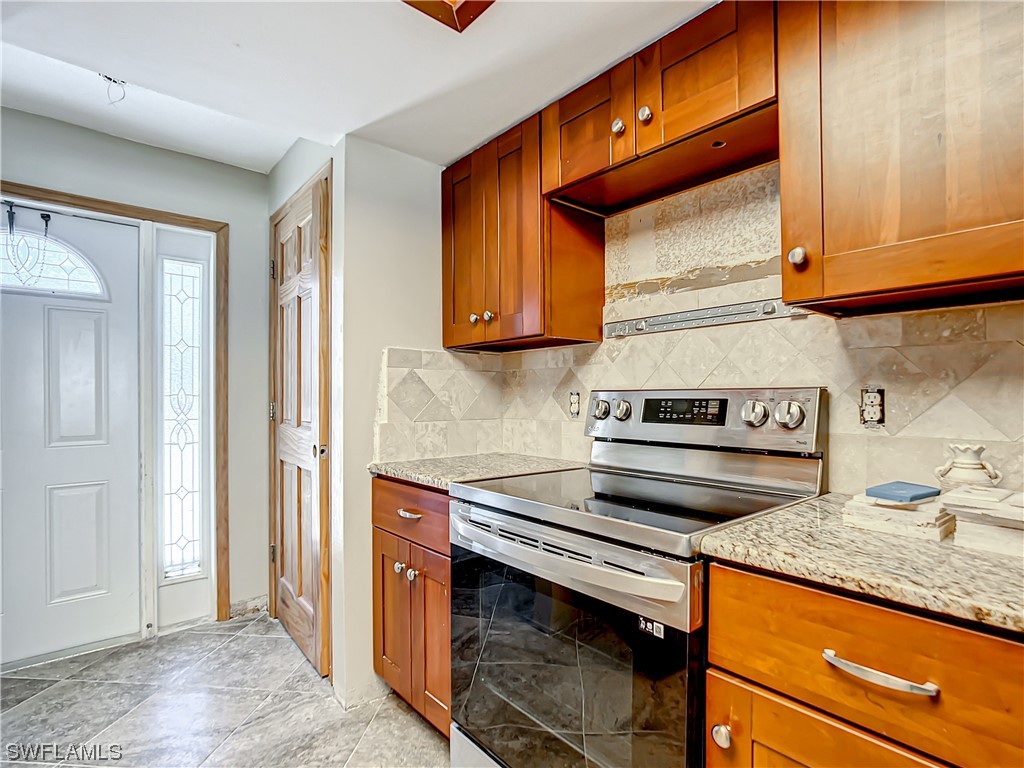 207 Redfish Road Fort Myers Beach, FL 33931 - Photo 5 of 50 a kitchen with stainless steel appliances granite countertop wooden cabinets and a stove top oven