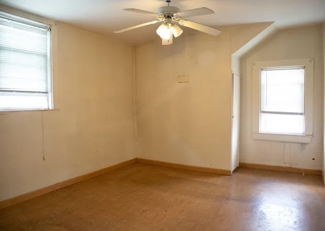 an empty room with a window and a fan